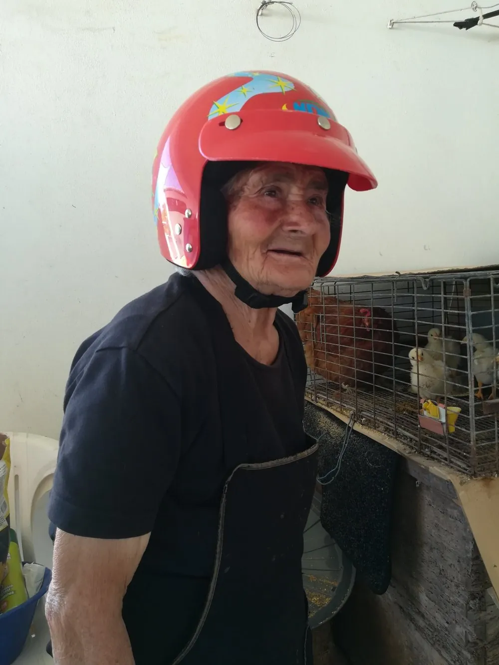 A Maria com um capacete vermelho, junto à capoeira, a sorrir.